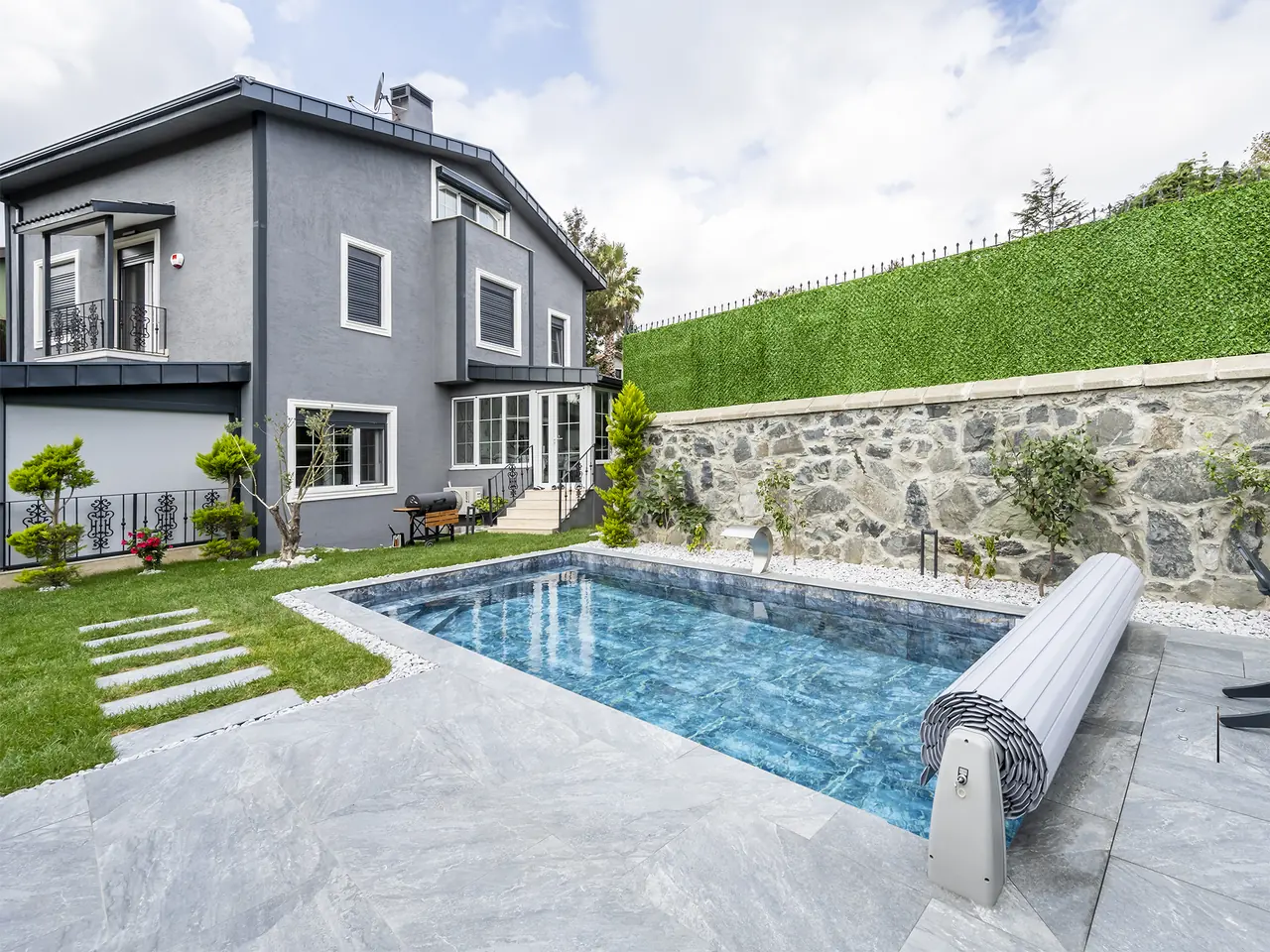 Pool and roller mechanism in front of a grey house – No1Pool