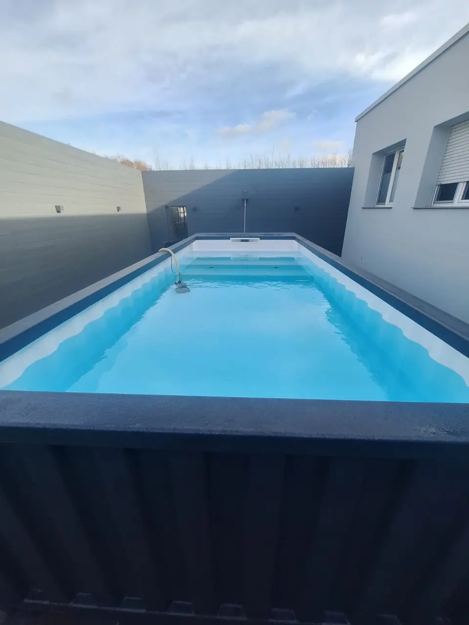 Gefüllter Containerpool neben einer Hausfassade – No1Pool
