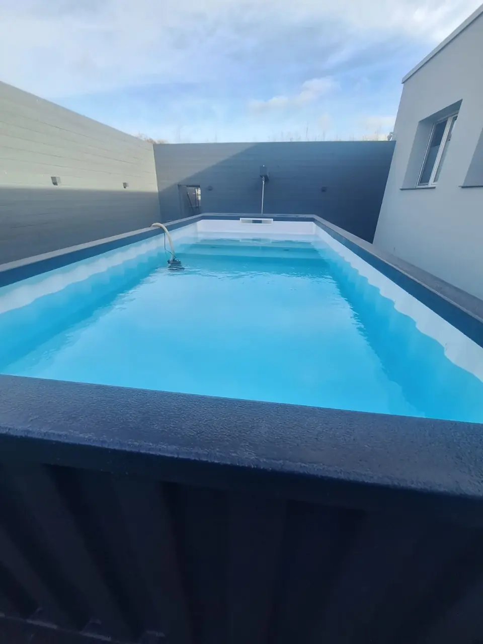 Blaue Wasserfläche zwischen Haus und Terrasse – No1Pool