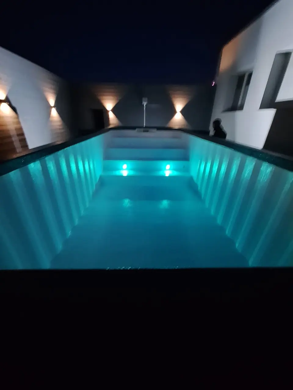 Türkis beleuchteter Containerpool am Abend – No1Pool
